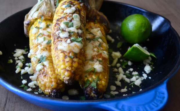{Fun, Yum & Frills} Mexican Street Corn - a savory and spicy side for your Cinco de Mayo or summer barbecue. Roasted corn covered in a mayo and sour cream sauce spiked with lime and cayenne roasted to perfection. Leave the husks on for a fun and easy handle!